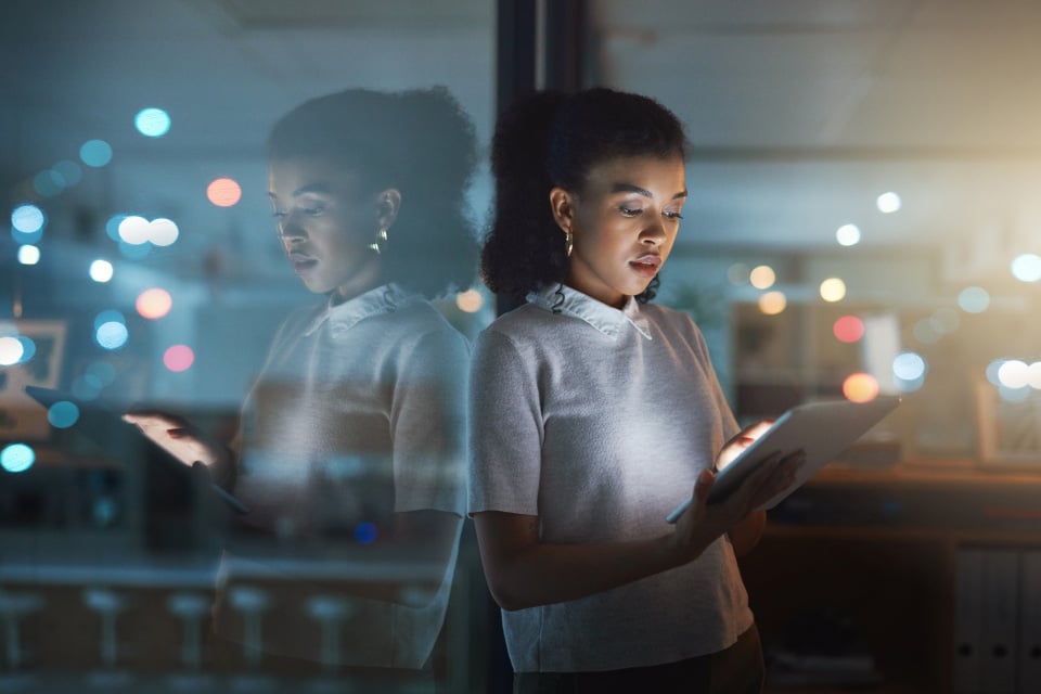 Text-Media_Young woman standing in front of dark skyline with phone nightlights 20240412 GLO EN